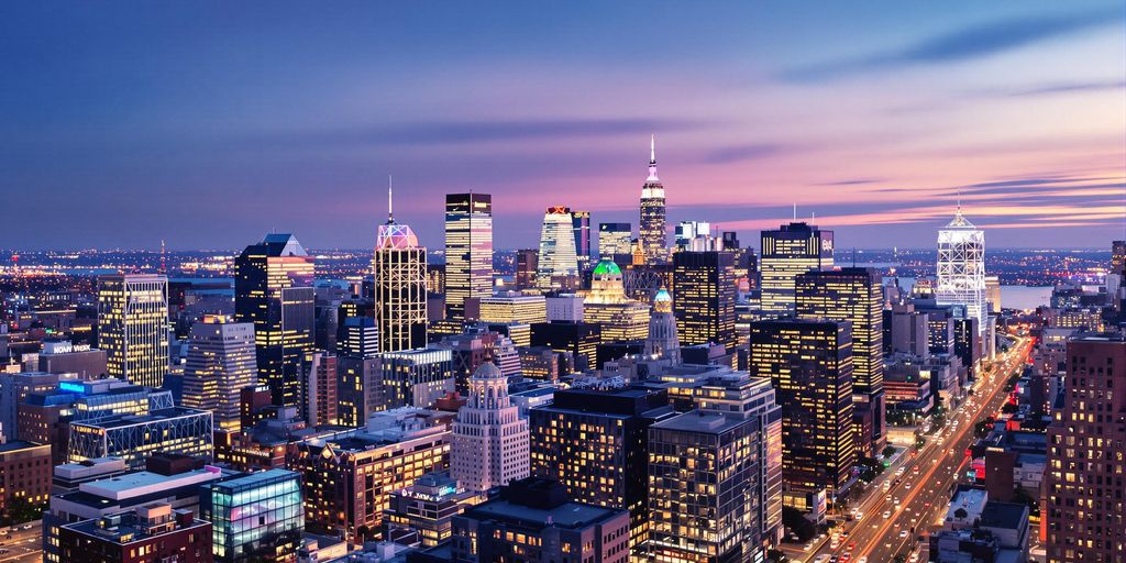 NYC skyscrapers glowing at dusk with vibrant digital billboard lights